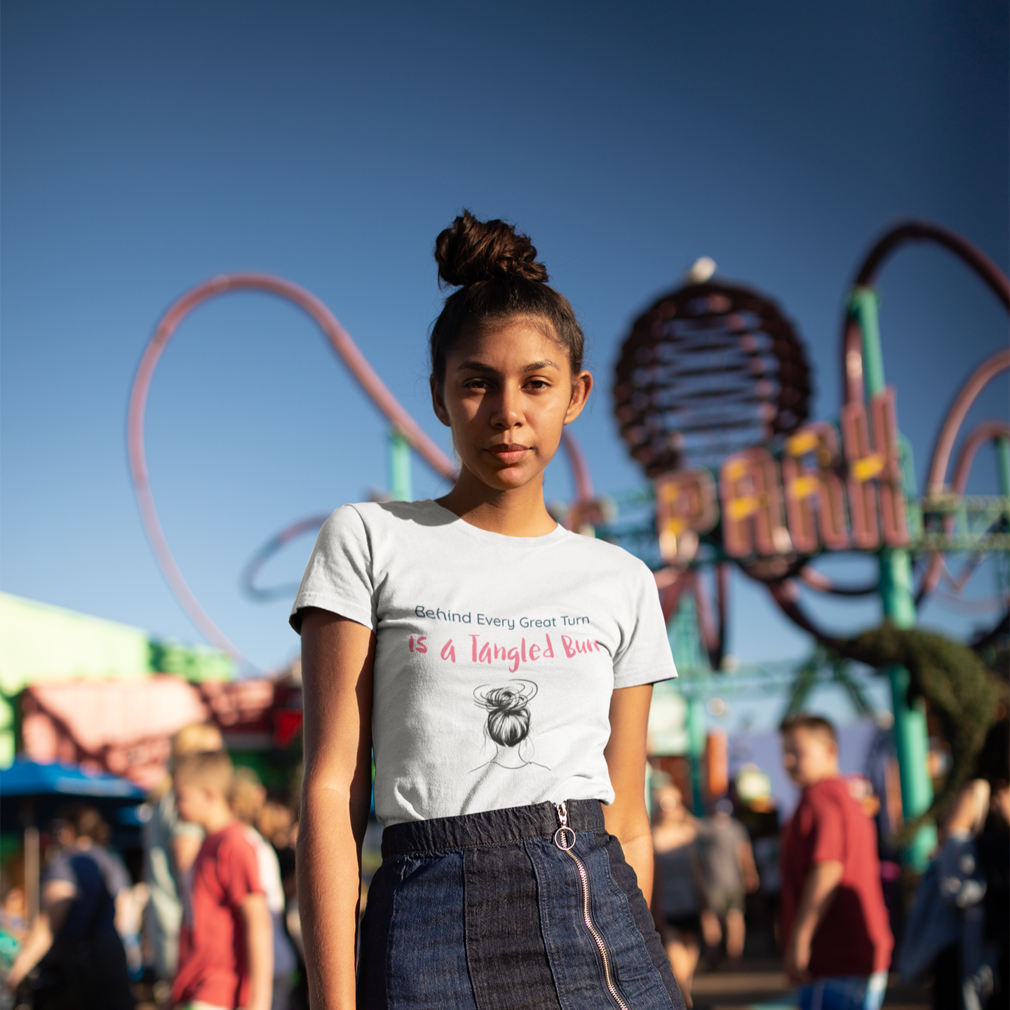 Woman wearing white dance t-shirt with the quote “Behind Every Great Turn is a Tangled Bun” in playful font