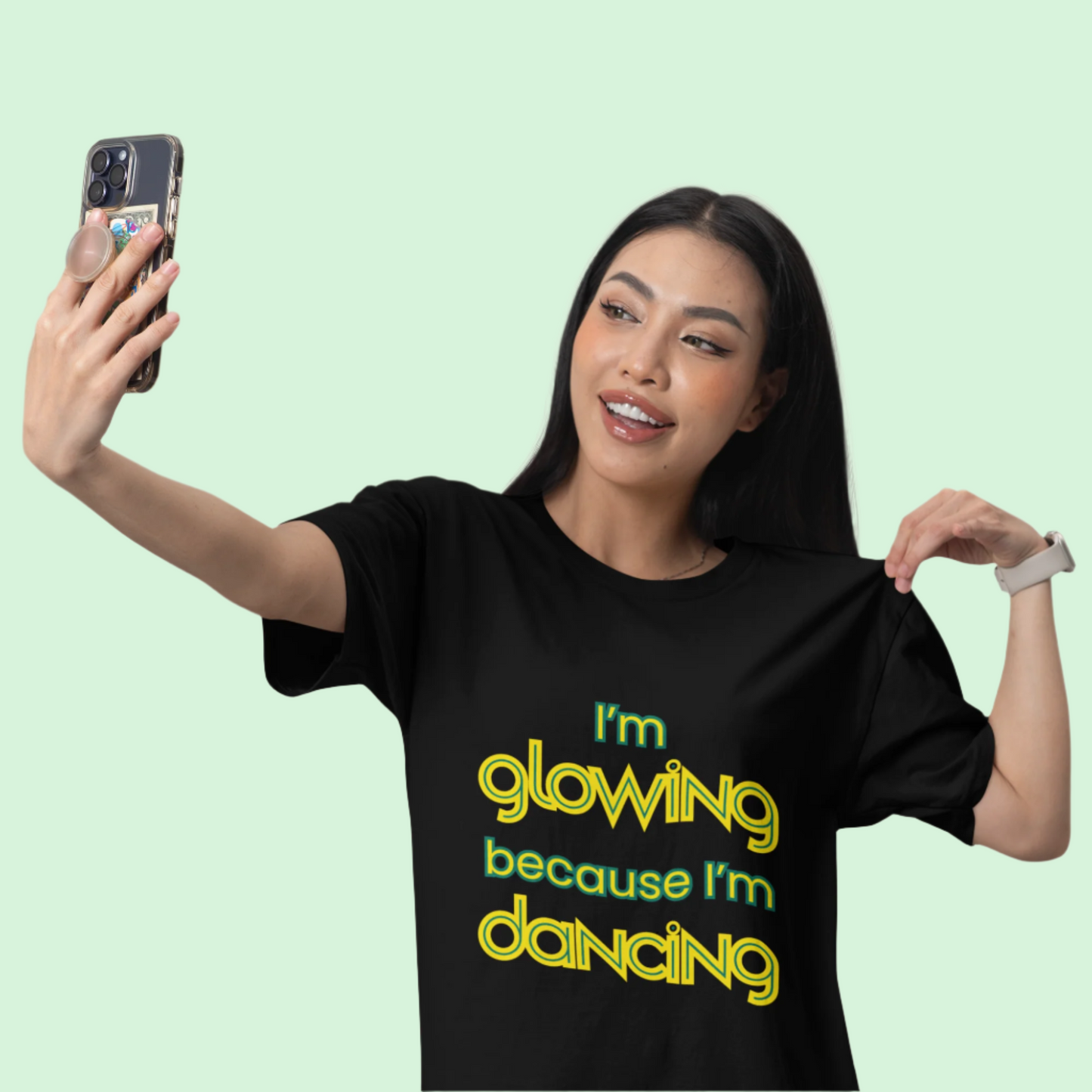Woman wearing black unisex dance t-shirt with the phrase “I’m Glowing Because I’m Dancing” in playful, radiant font. A cheerful and empowering design that captures the inner joy and confidence dancing brings.