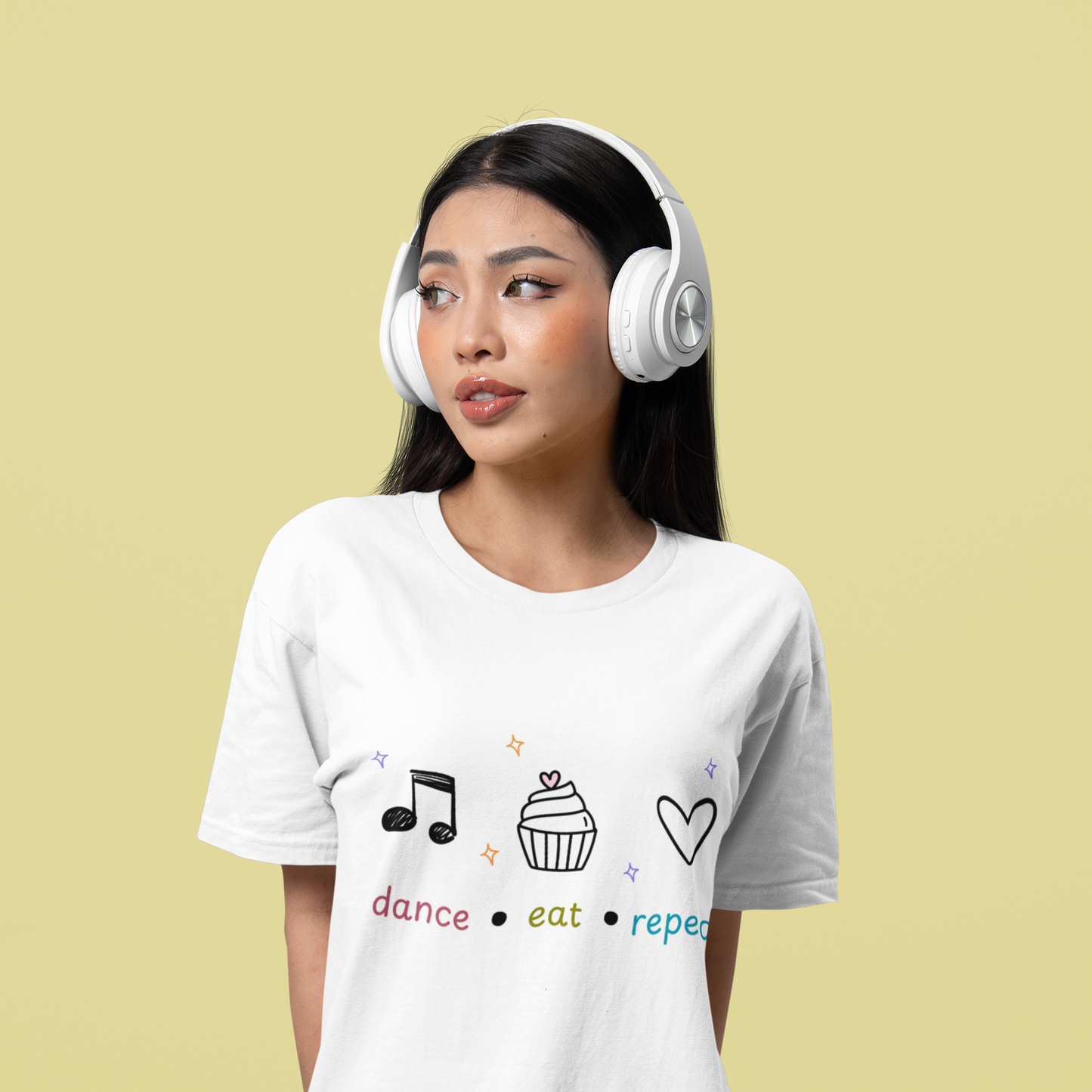 Woman wearing white dance t-shirt featuring dance eat repeat text with black icons of a music note, cupcake, and heart, designed for fun-loving dancers.