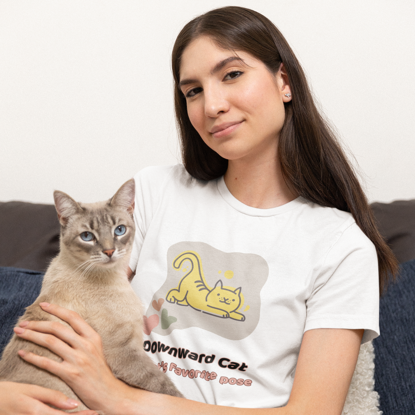 Woman holding a cat wearing a yoga t-shirt with a graphic design with phrase " Downward Cat My cat's favorite pose"