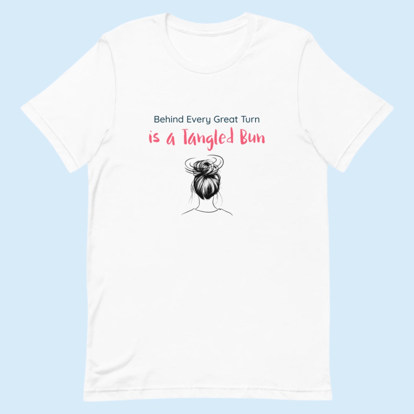 White dance t-shirt with the quote “Behind Every Great Turn is a Tangled Bun” in playful font, laid flat on a clean surface