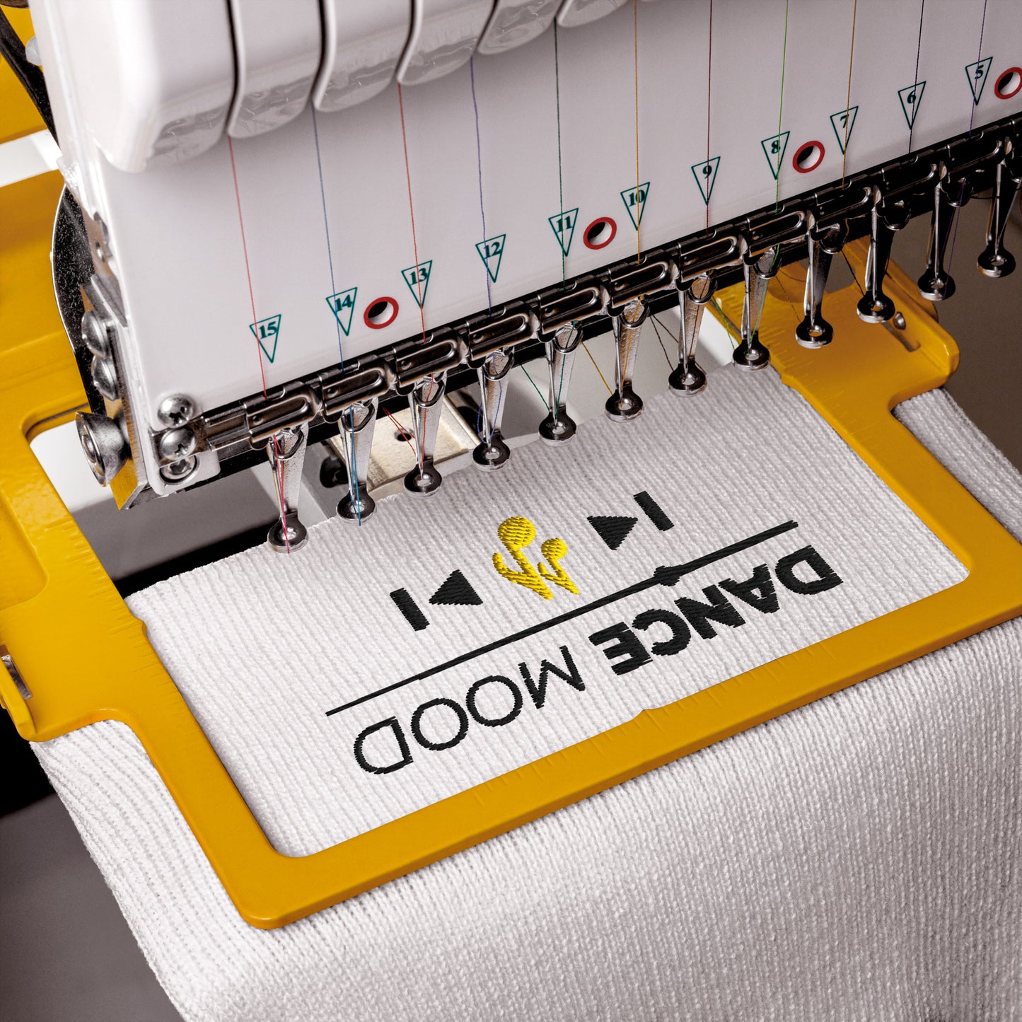 Embroidery machine stitching ‘Dance Mood On’ design with yellow music note on a white beanie.