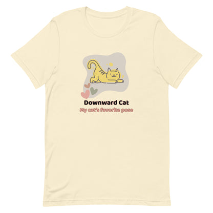 Natural unisex yoga t-shirt featuring a playful cartoon illustration of a cat doing a yoga stretch, paired with the text “Downward Cat: My Cat’s Favorite Pose.” 