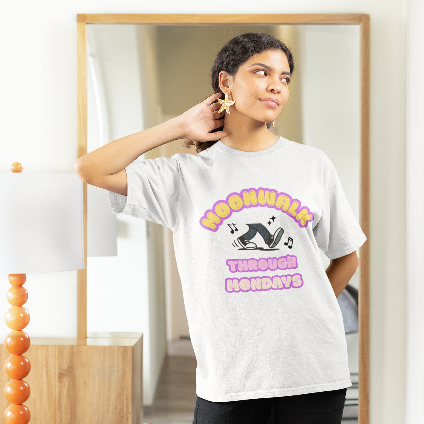 Woman wearing an unisex dance t-shirt with a graphic design saying "Moonwalk through Mondays" in front of a mirror.